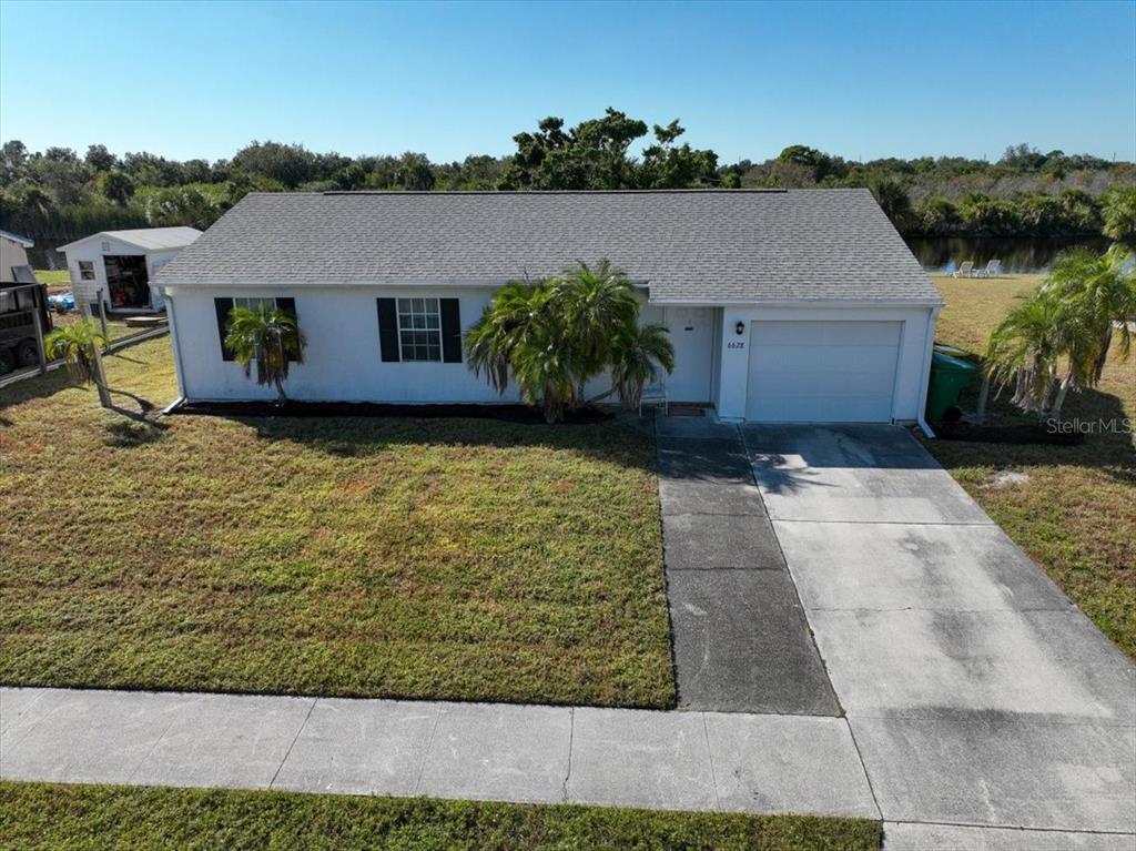 An aerial view of a single-story white house with a garage and a front lawn — 6628 THORMAN ROAD, PORT CHARLOTTE, FL