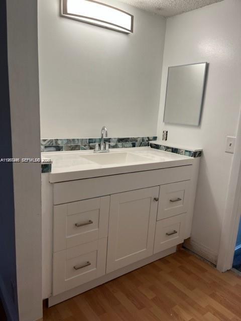 A bathroom vanity with a white cabinet, integrated sink, and blue decorative tile backsplash — 14020 SW 90th Ter # 14020, Miami FL 33186, MIAMI, FL