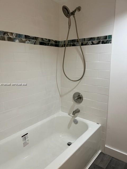A white bathtub with a handheld shower head and a decorative tile accent wall — 14020 SW 90th Ter # 14020, Miami FL 33186, MIAMI, FL