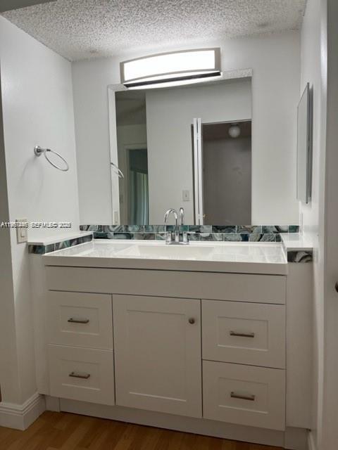 A bathroom vanity with a white cabinet, marble-patterned backsplash, and a rectangular mirror — 14020 SW 90th Ter # 14020, Miami FL 33186, MIAMI, FL