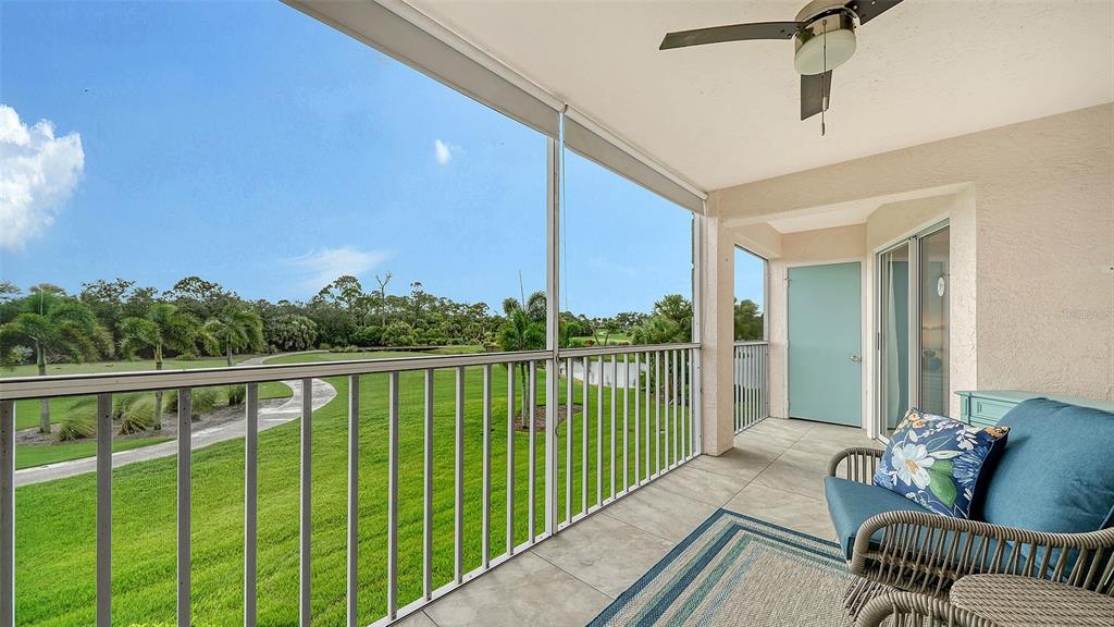A screened-in balcony features tile flooring, a ceiling fan, and views of a grassy landscape — 9320 CLUBSIDE CIRCLE UNIT 2205, SARASOTA, FL