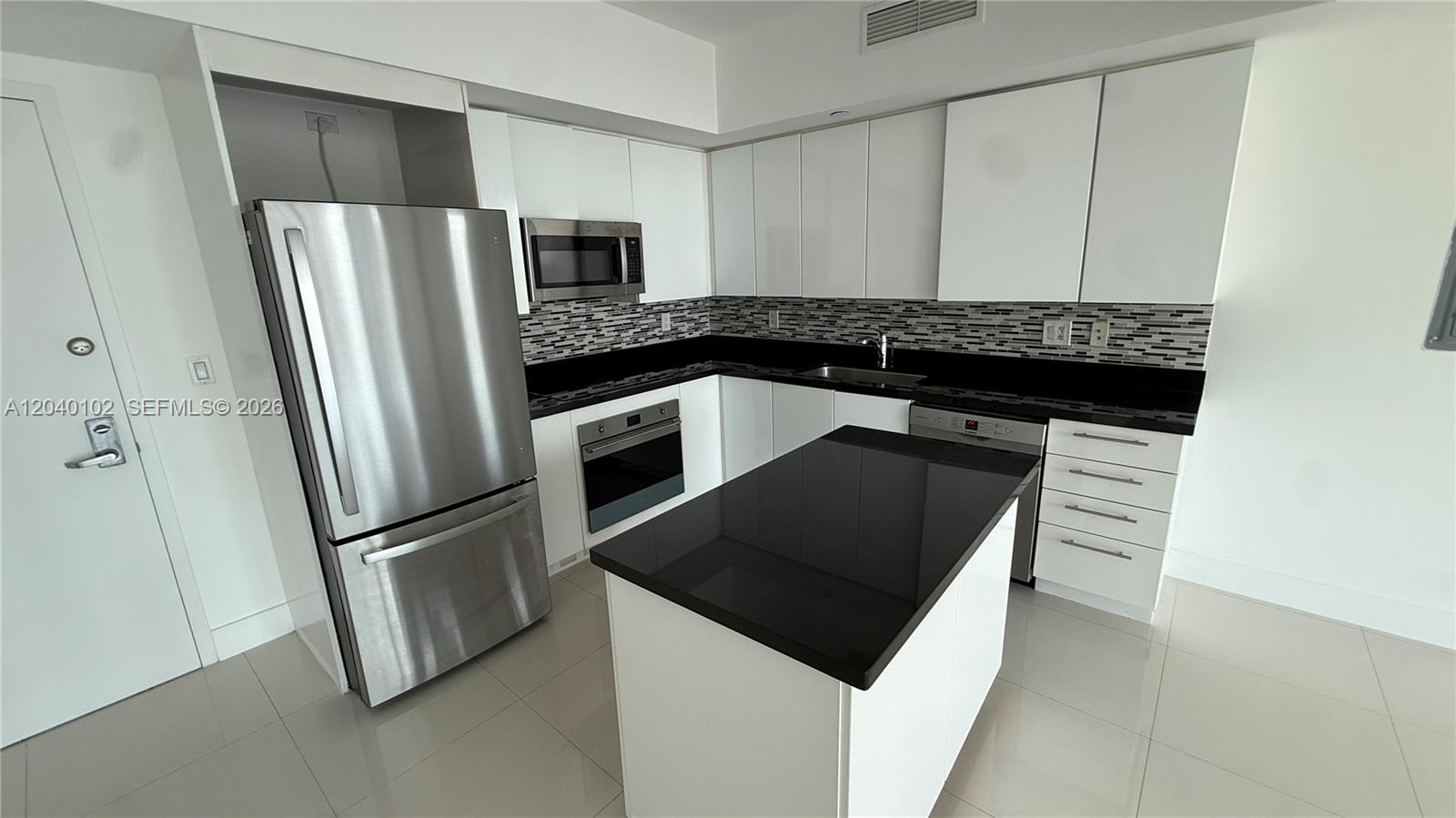 A modern kitchen features white cabinets, stainless steel appliances, and a black island countertop — 92 SW 3 Street # 3311, Miami FL 33130, MIAMI, FL