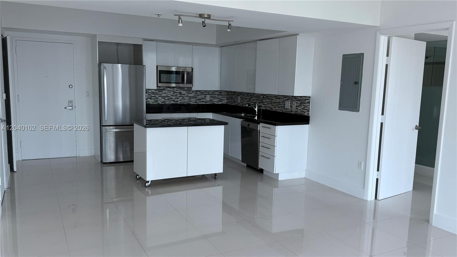 A modern kitchen features white cabinets, black countertops, stainless steel appliances, and a rolling island — 92 SW 3 Street # 3311, Miami FL 33130, MIAMI, FL