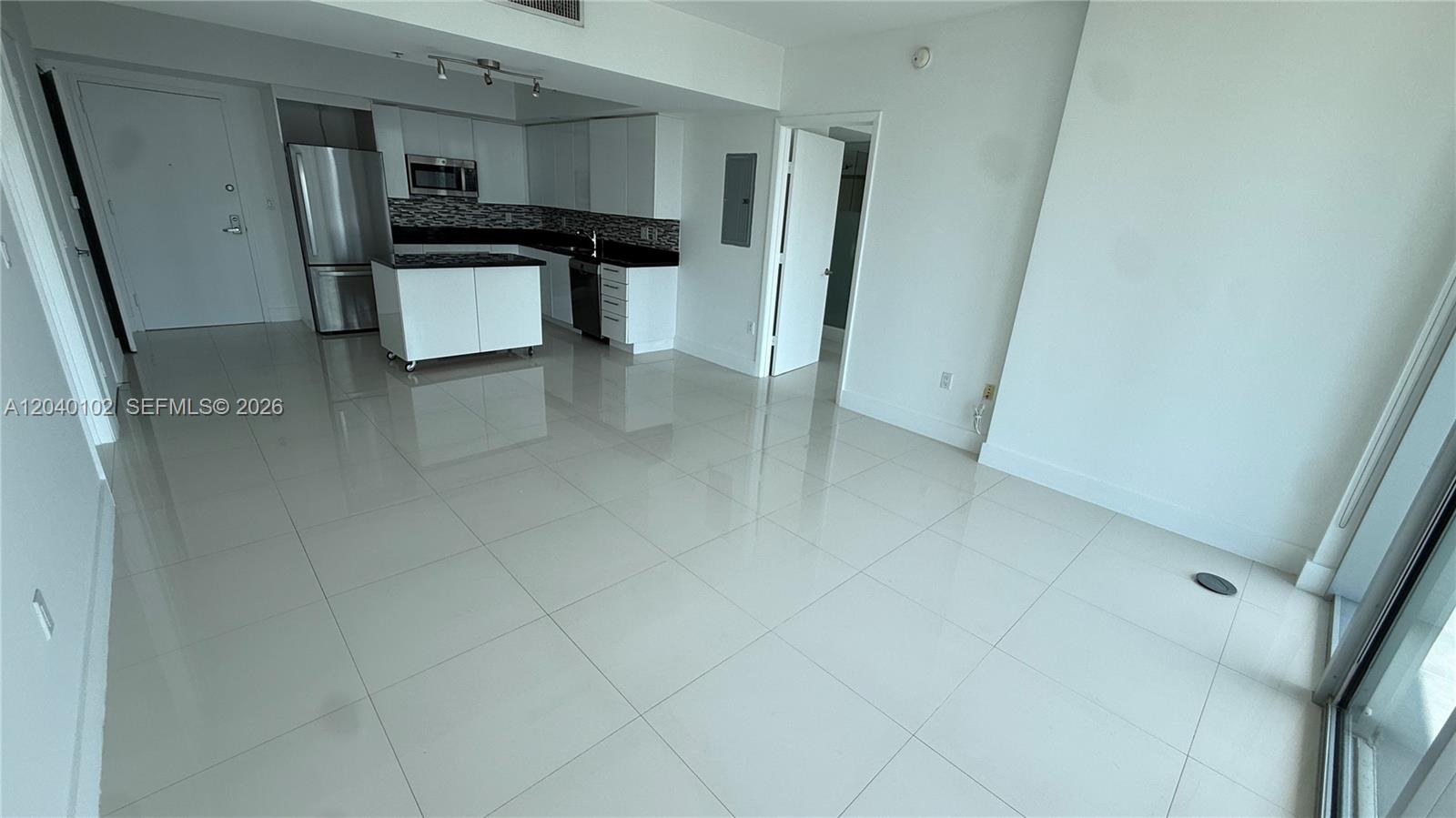 An open-concept kitchen with white cabinetry and stainless steel appliances overlooks a tiled living area — 92 SW 3 Street # 3311, Miami FL 33130, MIAMI, FL
