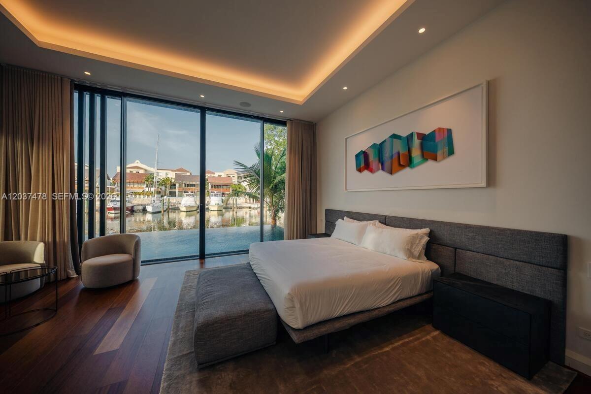 A modern bedroom features a large bed, floor-to-ceiling windows, and a view of a marina — 0 Marina, FL