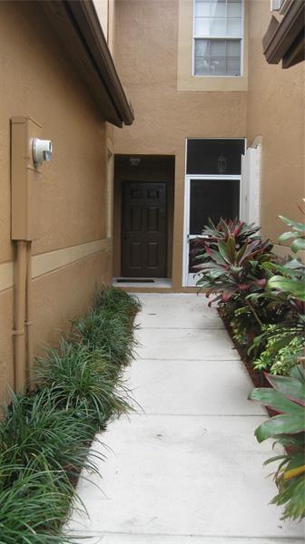 A concrete walkway leads to a dark brown front door and a screened-in entryway — 1348 Veracruz Lane # 8, Weston FL 33327, WESTON, FL