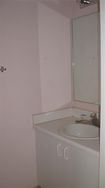 A bathroom vanity with a white countertop, sink, cabinet, and mirror against light pink walls — 1348 Veracruz Lane # 8, Weston FL 33327, WESTON, FL