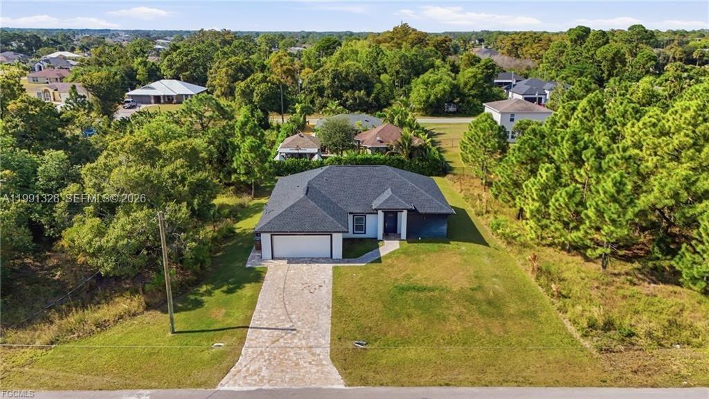 An aerial view of a single-story house with a paved driveway and a dark roof — 1013 ATHERTON AVE, Lehigh Acres FL 33971, LEHIGH ACRES, FL
