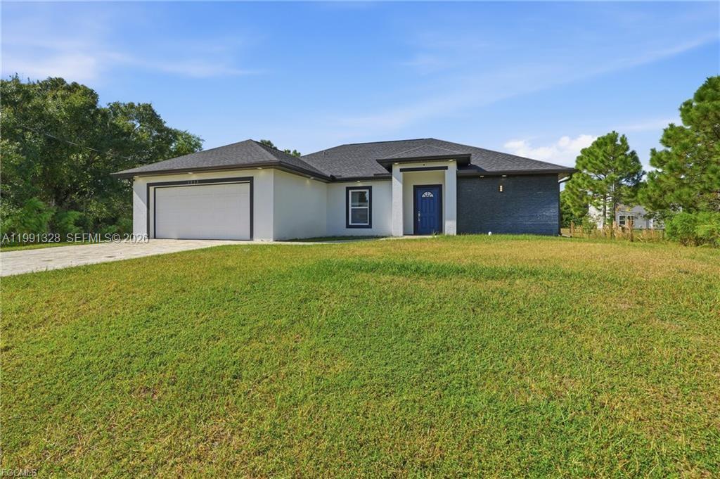 A single-story house with a white stucco facade, dark brick accents, and a two-car garage — 1013 ATHERTON AVE, Lehigh Acres FL 33971, LEHIGH ACRES, FL