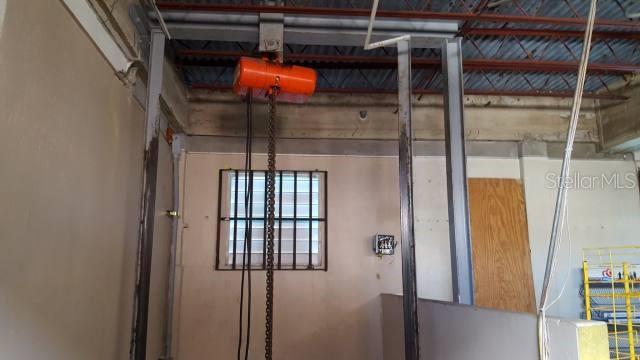 An industrial space features a ceiling-mounted orange chain hoist suspended between two metal support beams — GAUTIER BENITEZ ST. INT. INT. JIMENEZ SICARDO ST., CAGUAS, PR