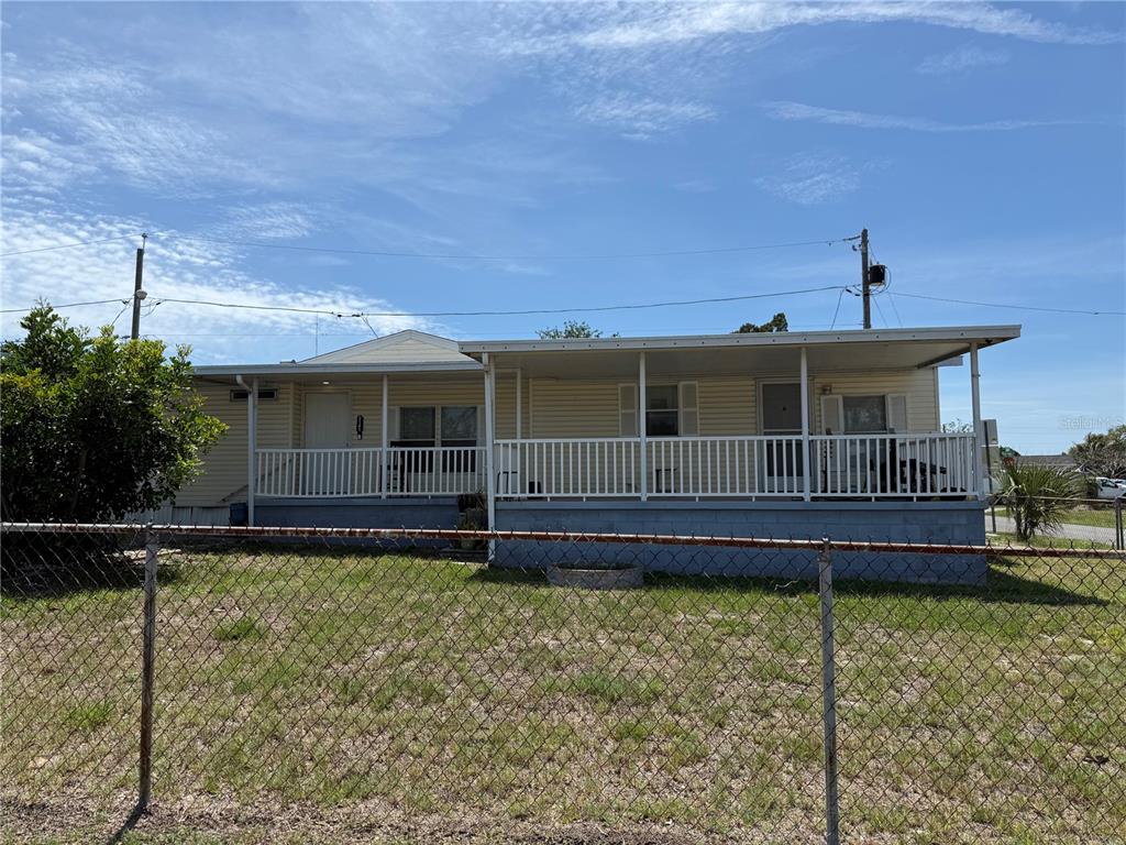 A single-story house with a covered front porch sits behind a chain-link fence — 2141 SPECK DRIVE, HOLIDAY, FL