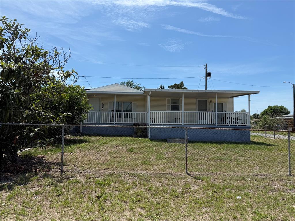 A single-story house with a covered porch sits behind a chain-link fence — 2141 SPECK DRIVE, HOLIDAY, FL