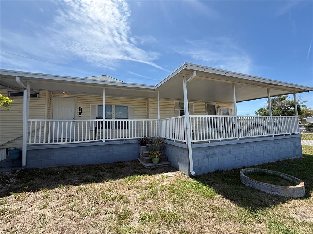 A single-story house with light yellow siding, a large covered porch, and a block foundation — 2141 SPECK DRIVE, HOLIDAY, FL