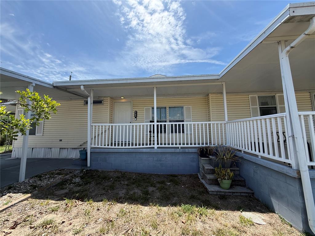 The exterior of a light yellow mobile home features a covered porch with white railings — 2141 SPECK DRIVE, HOLIDAY, FL