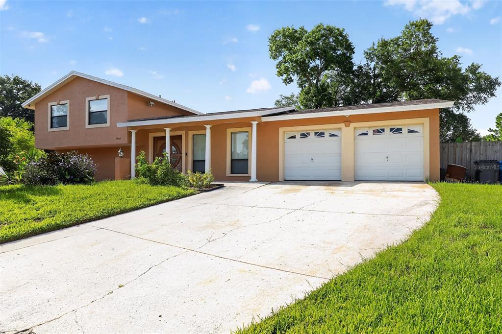A two-story house with a tan stucco exterior, a two-car garage, and a concrete driveway — 7001 BAYWOOD COURT, TAMPA, FL