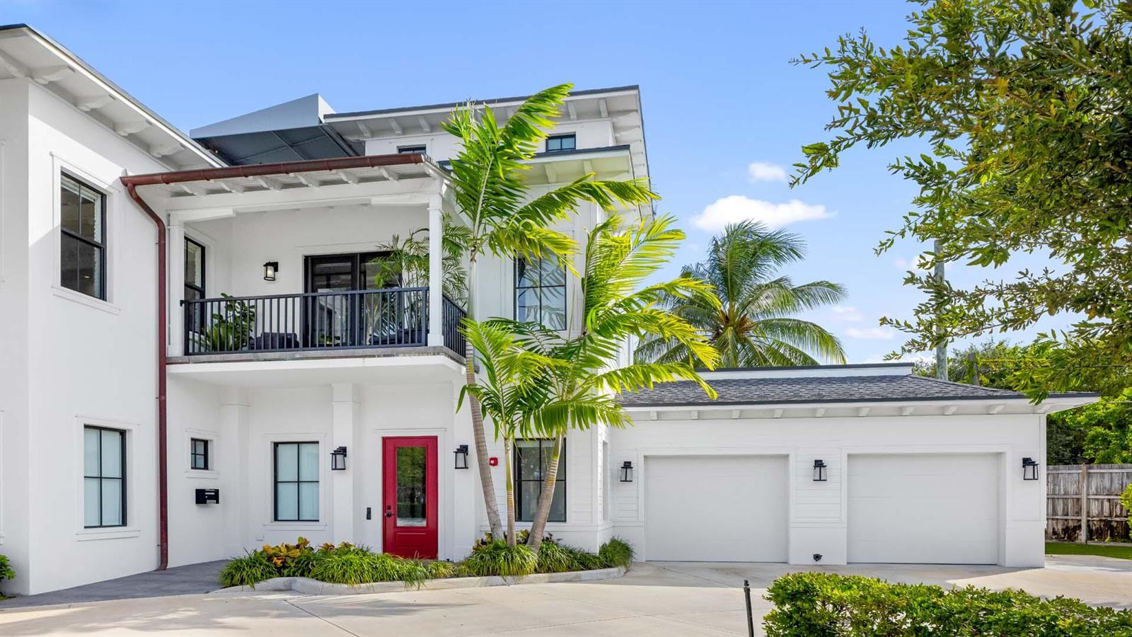 A white two-story house features a red front door, a balcony, and a two-car garage — 230 George Bush Boulevard, Delray Beach FL 33444, DELRAY BEACH, FL