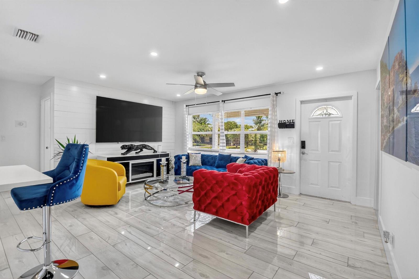 A living room features a red tufted sofa, blue sofa, yellow chair, and white flooring — 449 SW 4th Avenue, Boynton Beach FL 33435, BOYNTON BEACH, FL