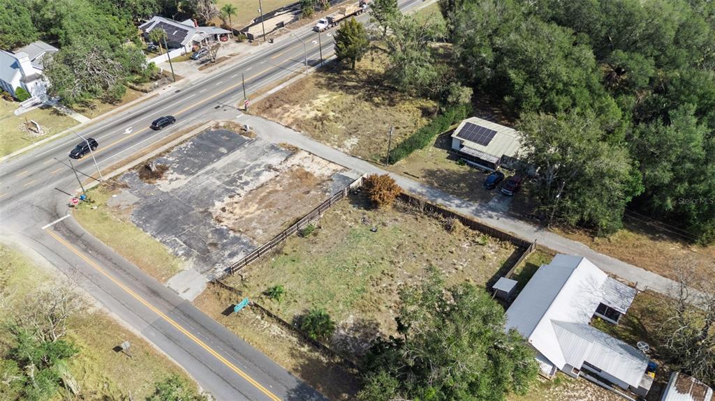 An aerial view shows a vacant lot with a paved area next to two houses — 331 W MYERS BOULEVARD, MASCOTTE, FL