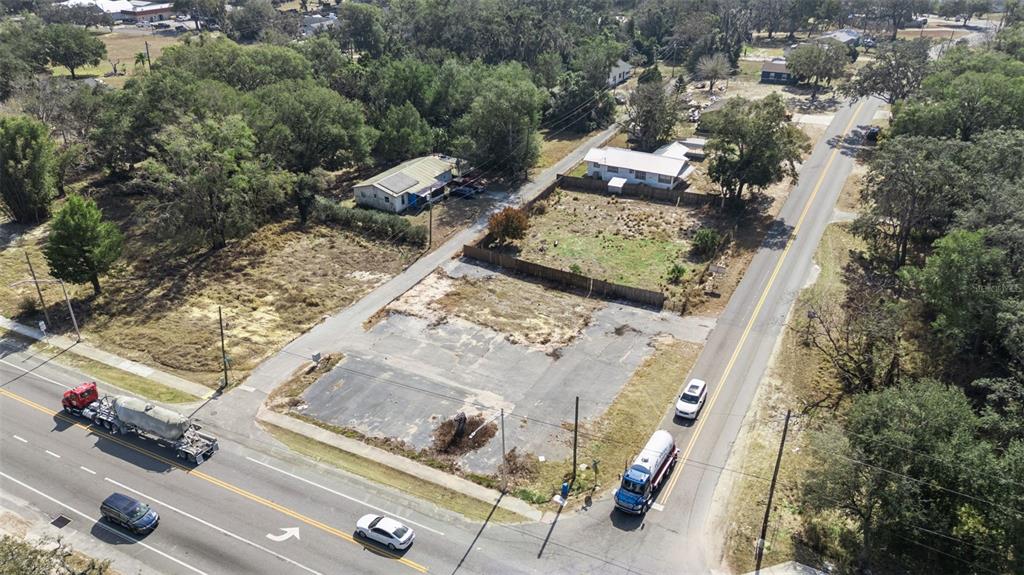 An aerial view shows a vacant paved lot situated between two roads and residential properties — 331 W MYERS BOULEVARD, MASCOTTE, FL