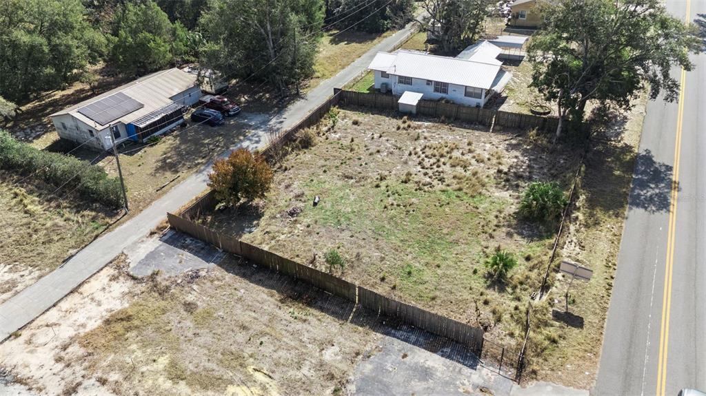 An aerial view shows a fenced, vacant rectangular lot situated between two residential houses — 331 W MYERS BOULEVARD, MASCOTTE, FL