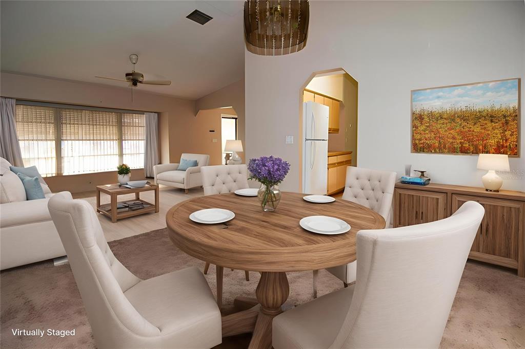 A dining area with a round wooden table and chairs opens into a living room — 1565 DORCHESTER STREET, PORT CHARLOTTE, FL