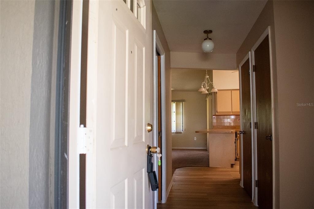 A view from an open front door looking into a hallway with wood-look flooring — 1565 DORCHESTER STREET, PORT CHARLOTTE, FL