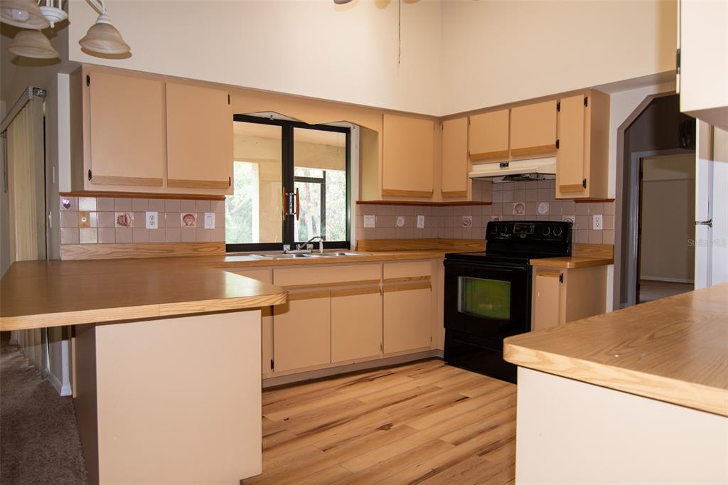 A kitchen with light-colored cabinets, laminate countertops, a black stove, and wood-look flooring — 1565 DORCHESTER STREET, PORT CHARLOTTE, FL