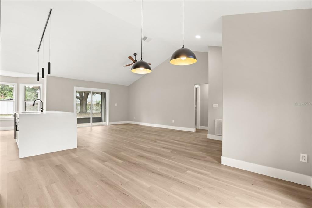An open-concept living area features light wood flooring, a white kitchen island, and vaulted ceilings — 13031 SCOTTISH PINE LANE, CLERMONT, FL