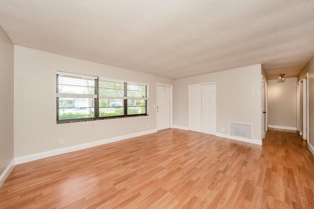 An empty room with light-colored walls, wood-look flooring, a large window, and white doors — BOCA RATON, FL