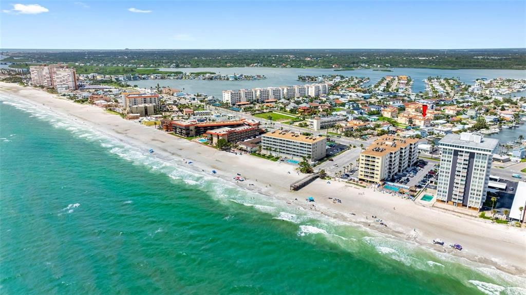 An aerial view shows a sandy beach, turquoise ocean, and several multi-story coastal apartment buildings — 146 175TH TERRACE DRIVE E, REDINGTON SHORES, FL