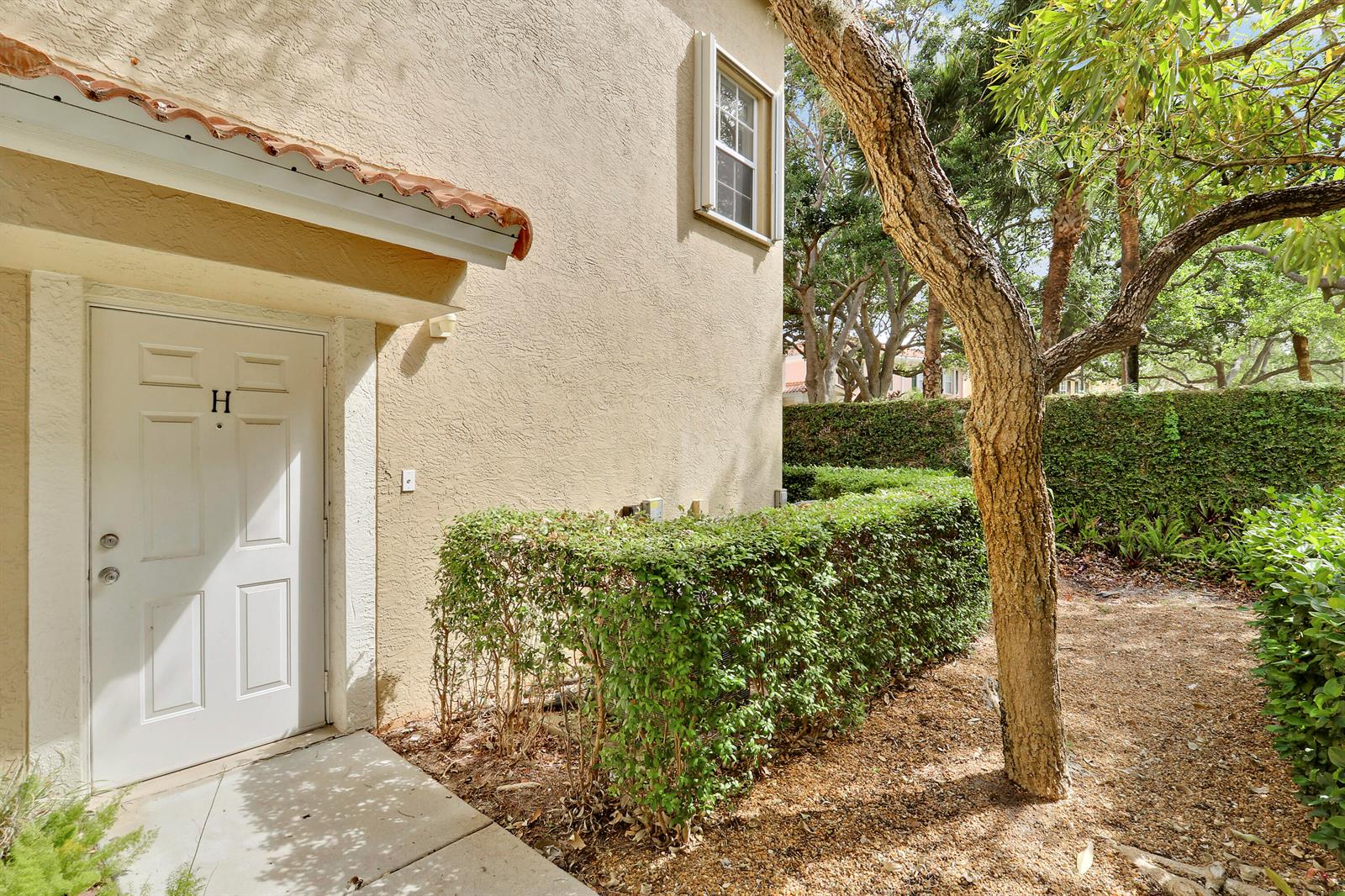 A white door labeled H is set into the beige stucco exterior of a building — 104 Lighthouse Circle # H, Tequesta FL 33469, TEQUESTA, FL