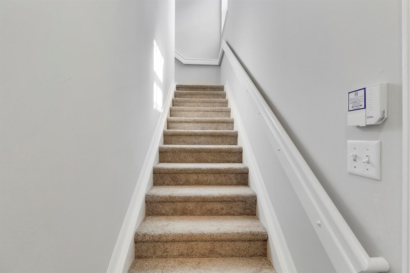 A carpeted staircase with white walls and a white handrail leads to an upper landing — 104 Lighthouse Circle # H, Tequesta FL 33469, TEQUESTA, FL