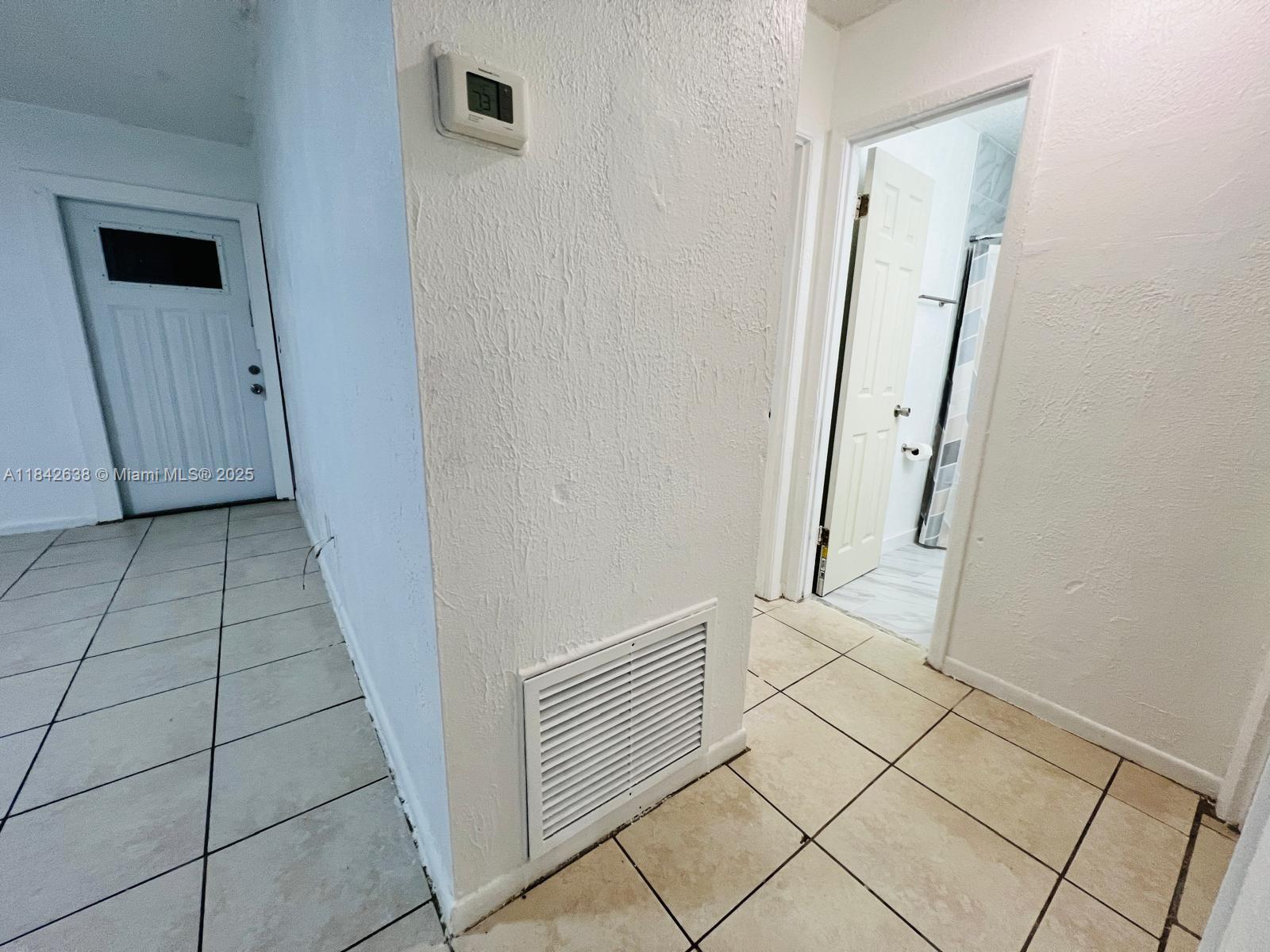 A hallway with tiled floors leads to a bathroom door and a white exterior door — 2019 COLMAR AVE, Sebring FL 33870, SEBRING, FL