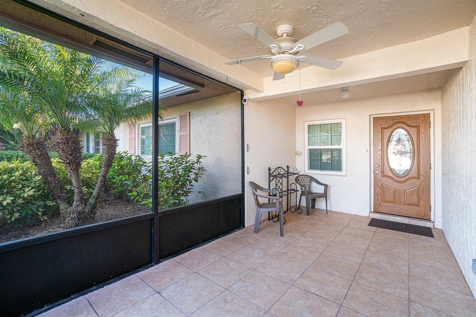 A covered patio features tiled flooring, a ceiling fan, two chairs, and a screened-in area — 13297b Vía Vulcanus, Delray Beach FL 33484, DELRAY BEACH, FL