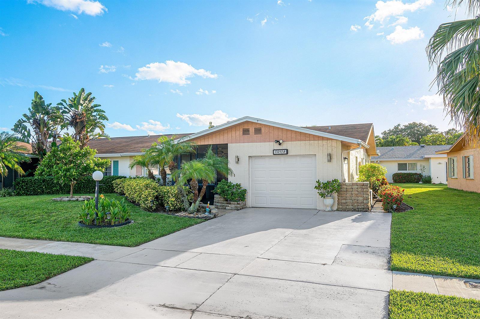 A single-story house with a white garage, beige siding, and a landscaped front yard — 13297b Vía Vulcanus, Delray Beach FL 33484, DELRAY BEACH, FL