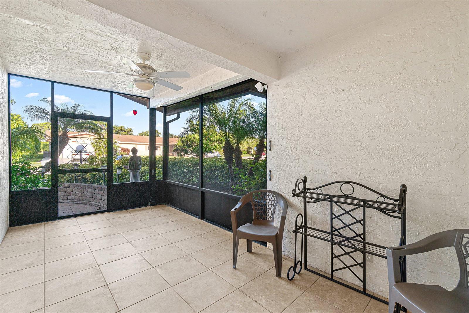 A screened-in patio with tiled flooring, a ceiling fan, and views of a landscaped yard — 13297b Vía Vulcanus, Delray Beach FL 33484, DELRAY BEACH, FL