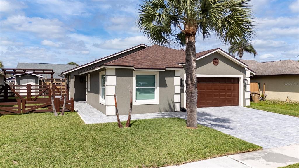 A single-story house with a gray exterior, white trim, a brown roof, and a driveway — 4980 WARRIOR LANE, KISSIMMEE, FL
