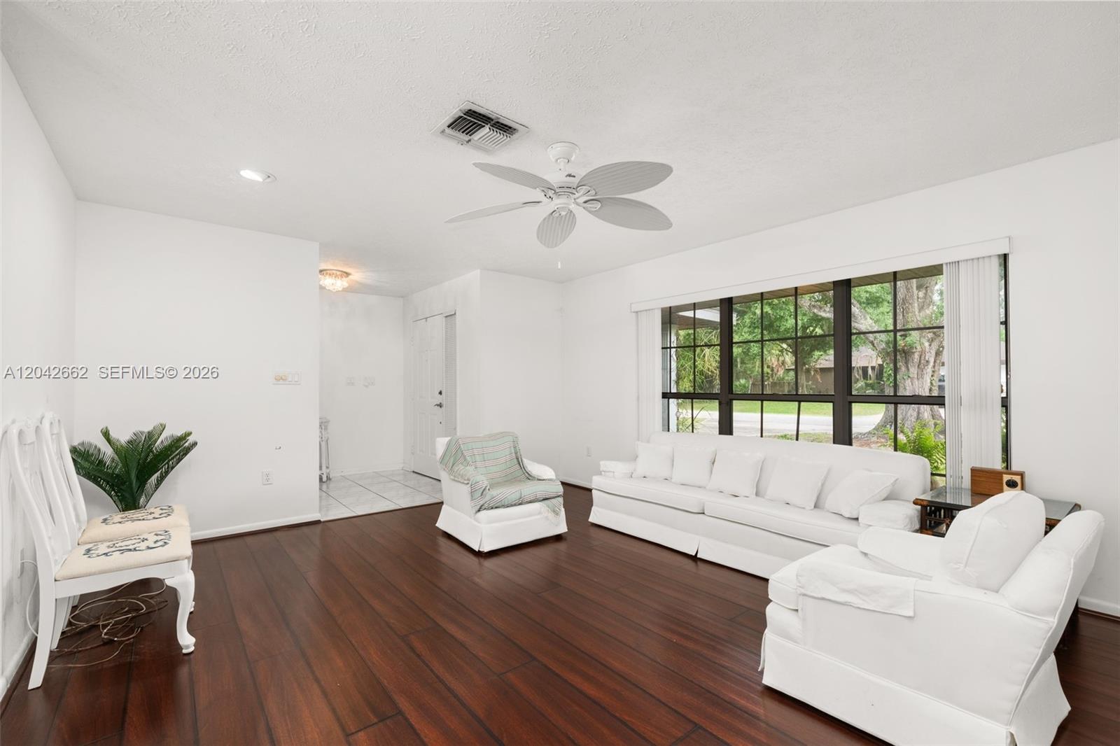 A living room features white furniture, dark wood flooring, and a large window — 4524 Harder Avenue, Sebring FL 33875, SEBRING, FL
