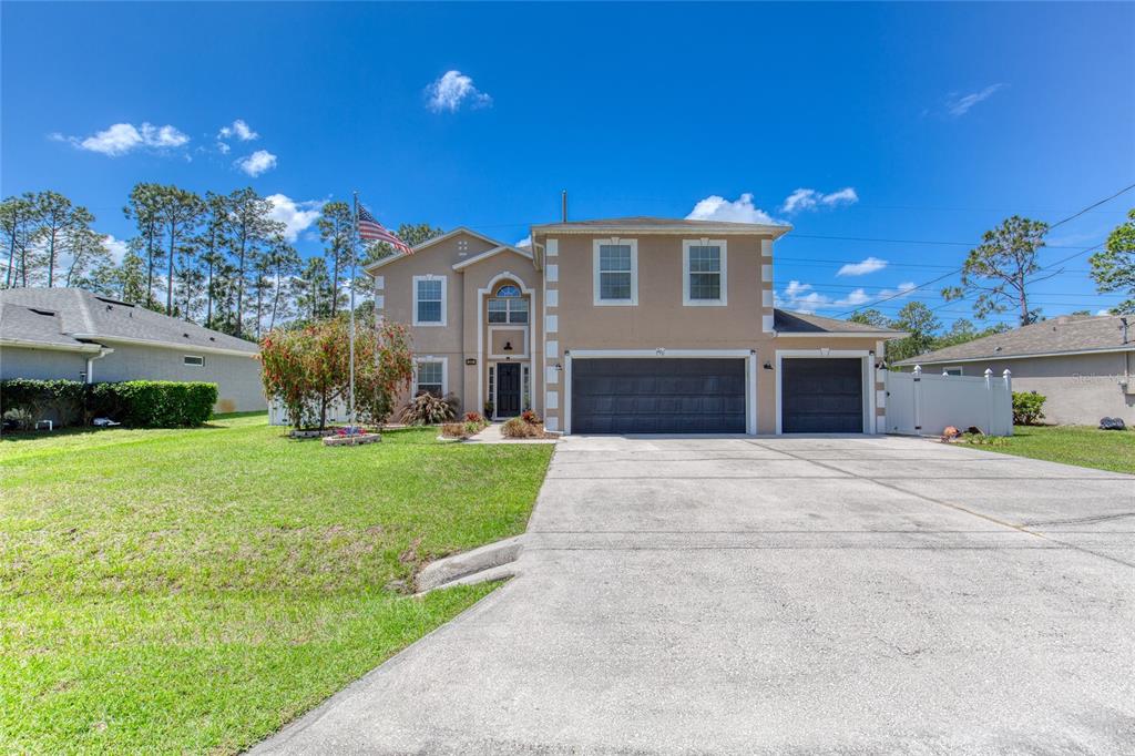 A two-story house with a tan exterior, a three-car garage, and a large front lawn — 201 UNDERWOOD TRAIL, PALM COAST, FL
