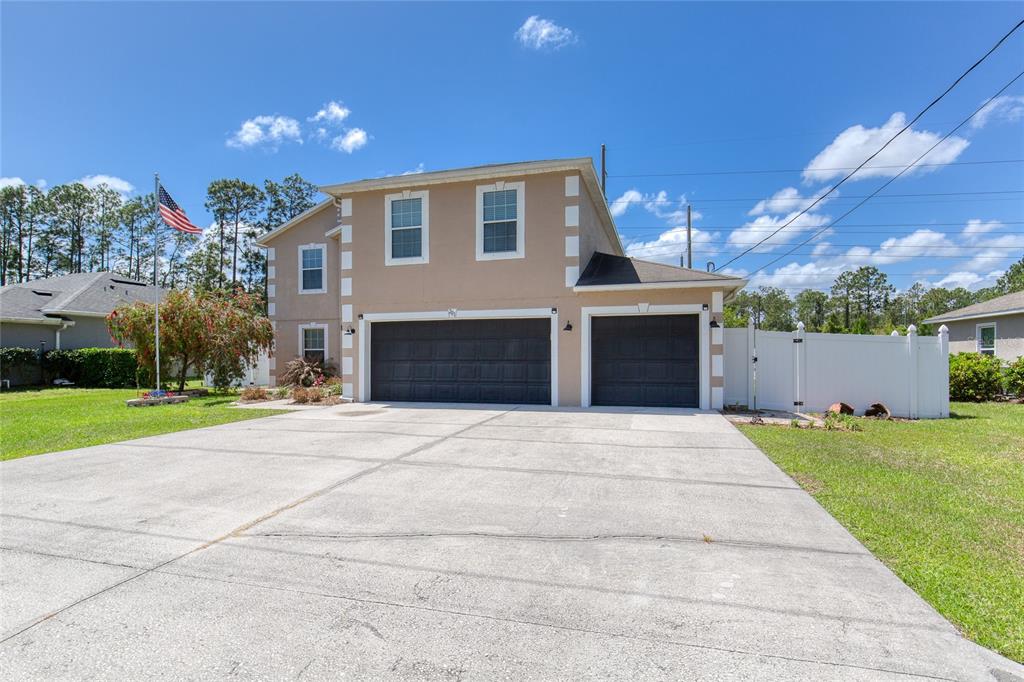 A two-story house with a three-car garage and a concrete driveway under a blue sky — 201 UNDERWOOD TRAIL, PALM COAST, FL