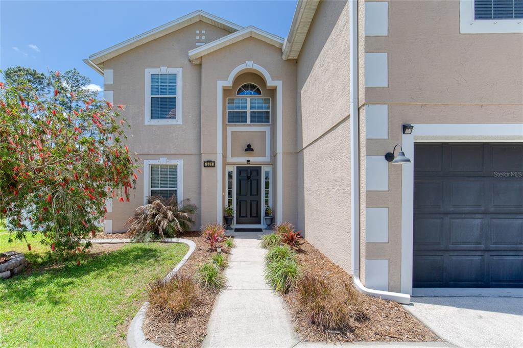 A two-story house exterior features a dark front door, arched entryway, and attached garage — 201 UNDERWOOD TRAIL, PALM COAST, FL