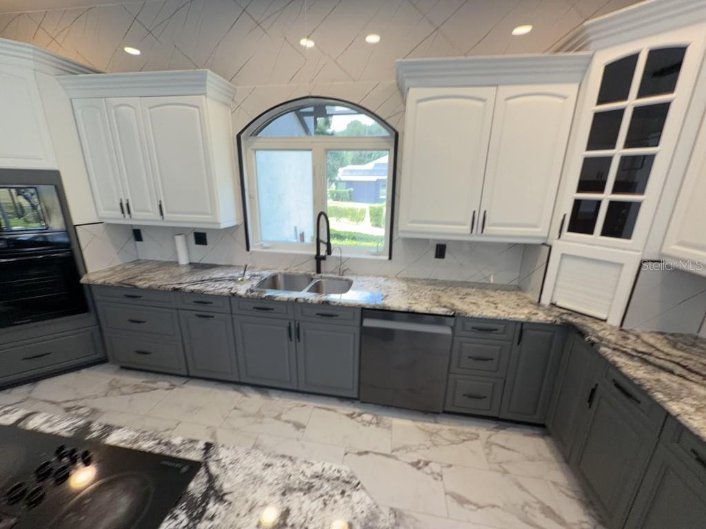 A kitchen features white upper cabinets, gray lower cabinets, granite countertops, and a large window — 8131 VINELAND OAKS BOULEVARD, ORLANDO, FL