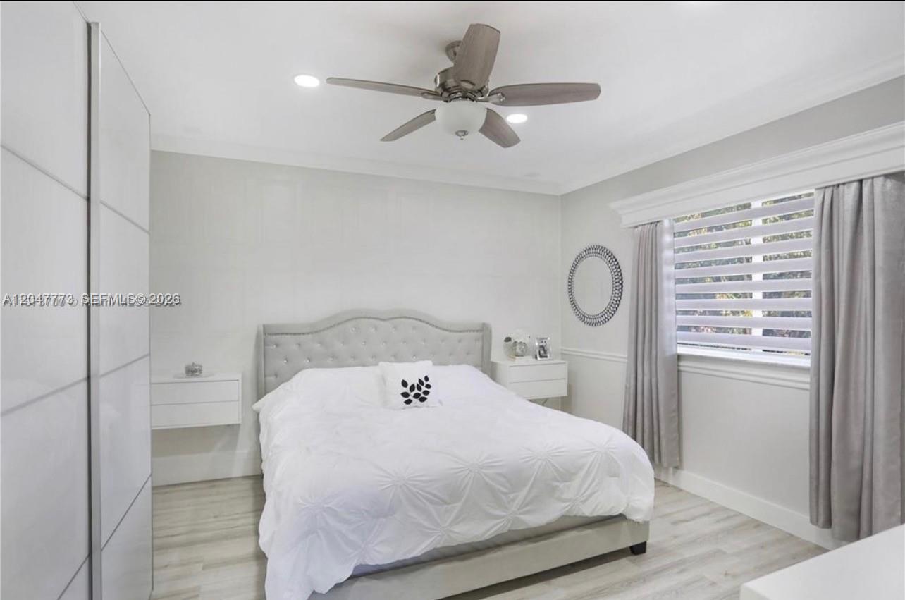 A bedroom features a tufted headboard, white bedding, floating nightstands, and a ceiling fan — 2535 NE 41st Ave, Homestead FL 33033, HOMESTEAD, FL