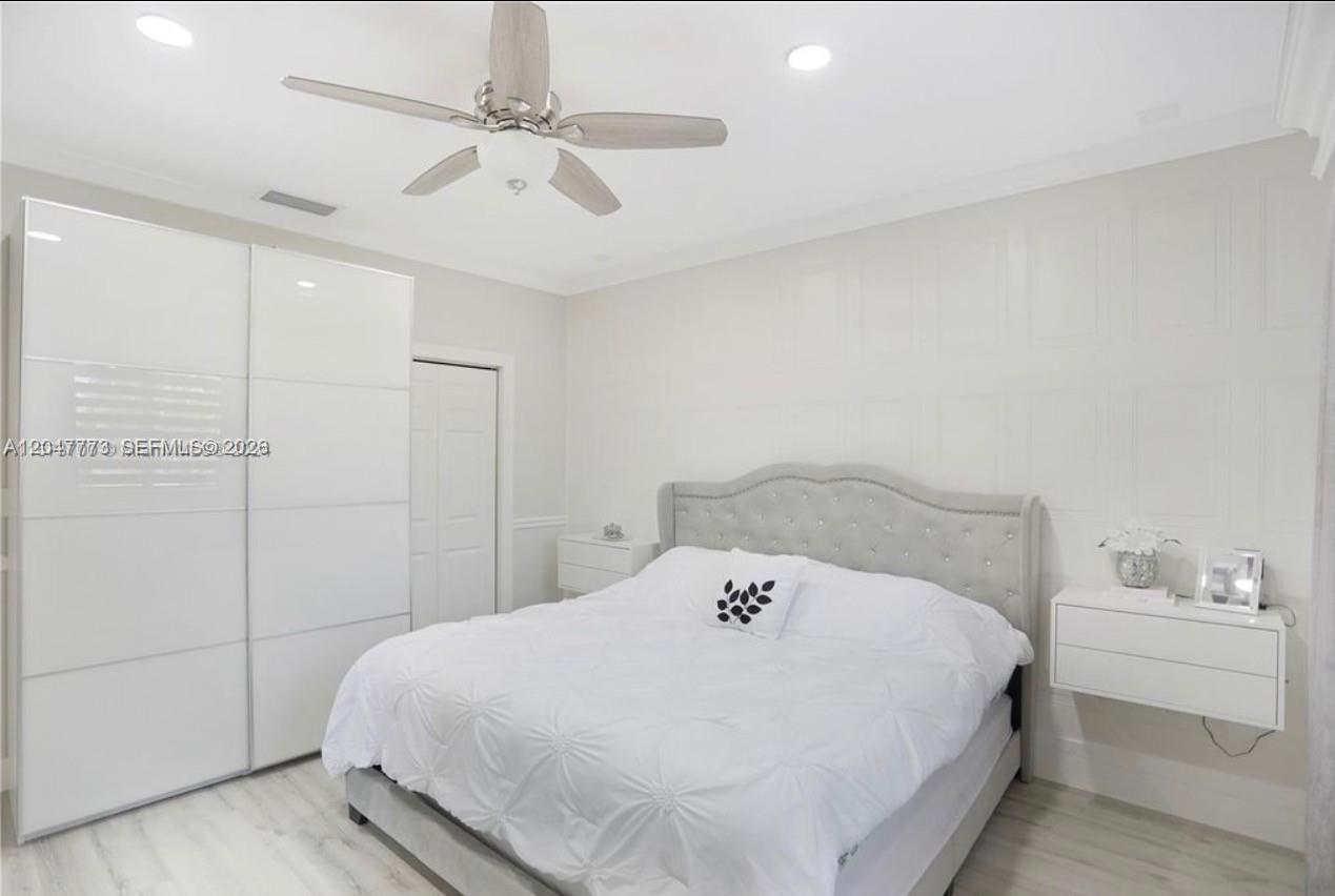 A bedroom features a tufted gray headboard, white bedding, a large wardrobe, and light flooring — 2535 NE 41st Ave, Homestead FL 33033, HOMESTEAD, FL