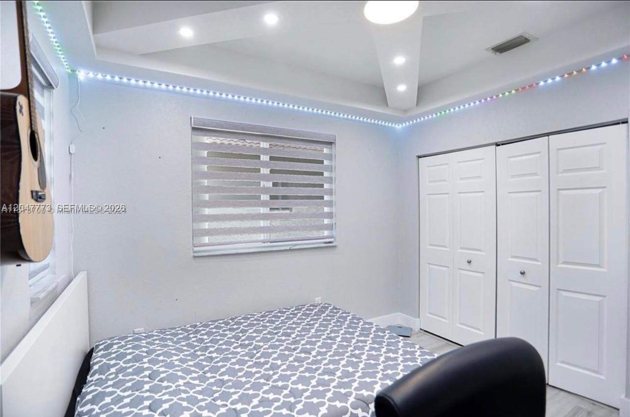A bedroom features a bed, a window with zebra blinds, and LED ceiling lighting — 2535 NE 41st Ave, Homestead FL 33033, HOMESTEAD, FL