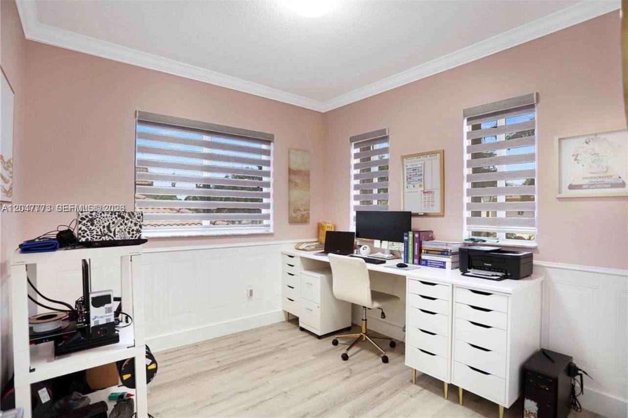 A home office features light pink walls, white wainscoting, wood-look flooring, and a white desk — 2535 NE 41st Ave, Homestead FL 33033, HOMESTEAD, FL