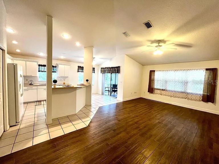 An open-concept kitchen with tile flooring transitions into a living area with wood-look floors — 1485 DONEGAN ROAD, LARGO, FL