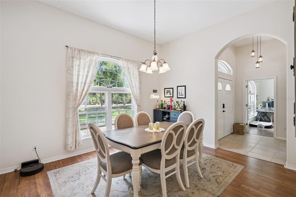 A dining room features a wooden table, six chairs, a bar cabinet, and hardwood floors — 5880 NOLAN ROAD, SANFORD, FL