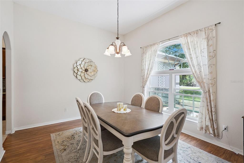 A dining room features a wooden table, six chairs, a chandelier, and a large window — 5880 NOLAN ROAD, SANFORD, FL