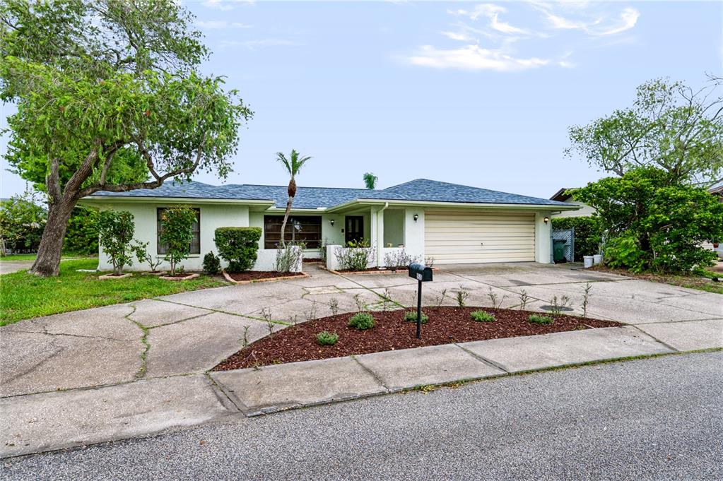 A single-story house with a light-colored exterior, a two-car garage, and a circular concrete driveway — 9520 LAKE CHRISTINA LANE, PORT RICHEY, FL